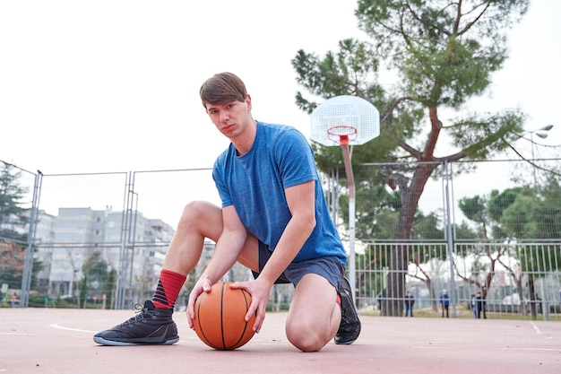 Détail tiré d'un jeune homme tenant un ballon tout en s'agenouillant sur un terrain de basket