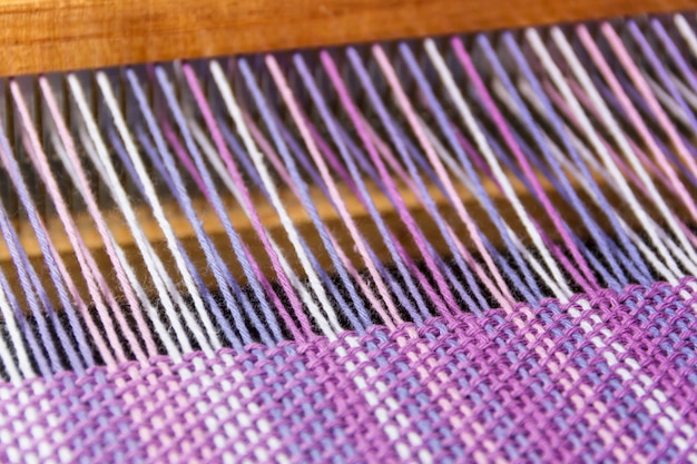 détail de tissu dans le peigne à tisser avec des couleurs ultraviolettes et lilas