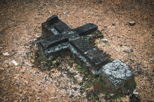 Détail d'une tombe dans un cimetière. Vieille croix ruinée au sol. Cimetière abandonné. Catholicisme, Orthodoxie, Christianisme