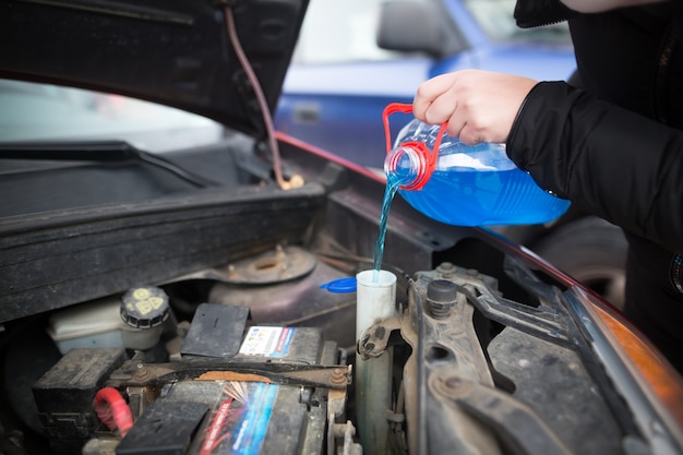 Détail sur verser le lave-glace liquide antigel dans la voiture sale du réservoir d'eau antigel bleu et rouge, concept de voiture