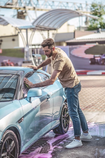 Détaillant de voiture concentré lavant une automobile client à l'extérieur