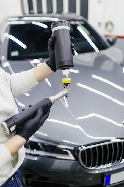 Détaillant de voiture - Travailleur avec polisseuse orbitale dans un atelier de réparation automobile. Mise au point sélective.