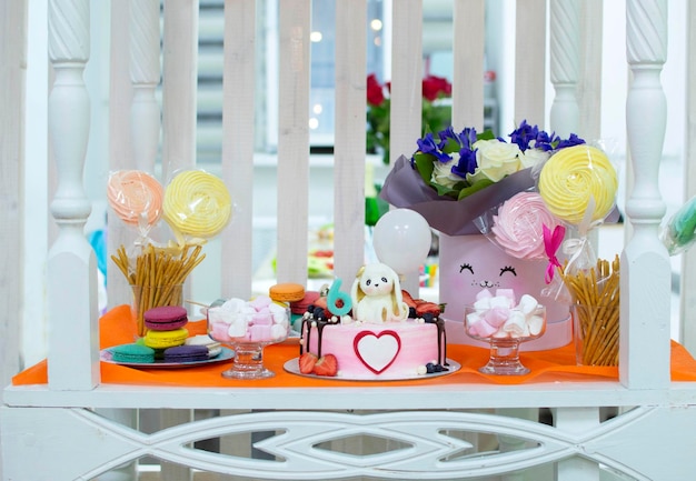 Photo détails d'une délicieuse barre de chocolat avec cruches de bonbons, biscuits et guimauves, bonbons, gaufres, biscuits et macarons, le concept de bonbons pour l'anniversaire d'un enfant. célébrer une fille de six ans.