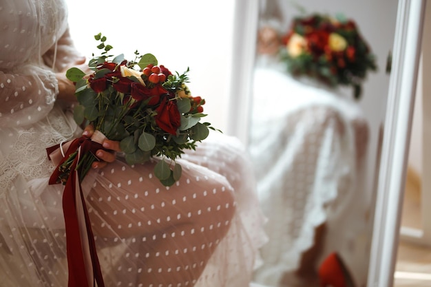 Détails du jour du mariage La mariée en robe blanche élégante tient un bouquet de mariage de fleurs dans les mains