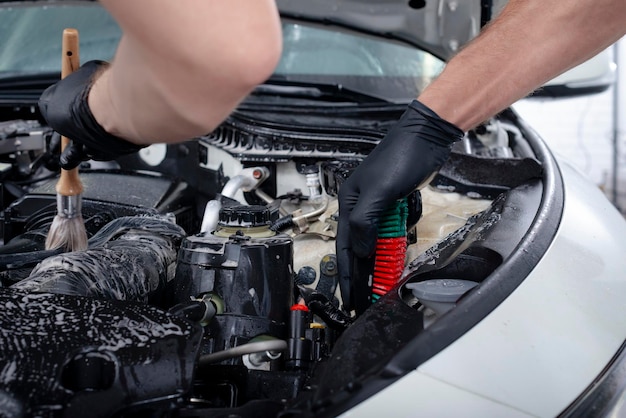 Détails de l'entretien de la voiture nettoyage du moteur avec la mousse et une brosse