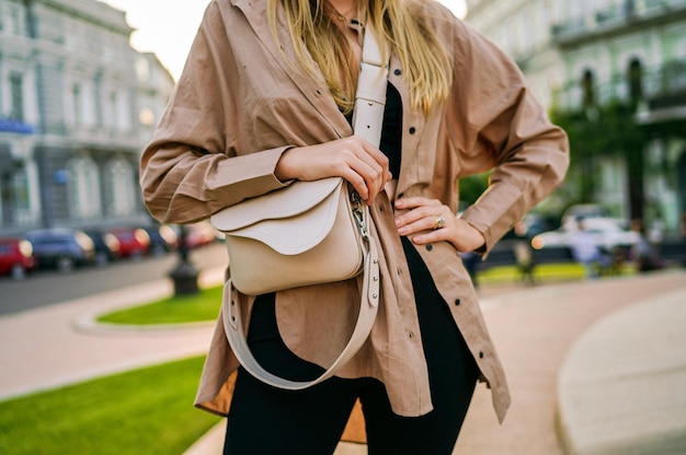 Détails de la mode d'une femme tenant un sac portant une tenue minimaliste élégante posant à l'extérieur