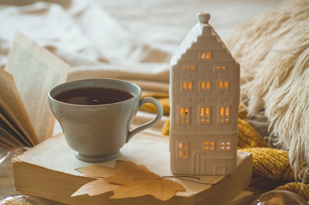 Détails de la vie encore à l'intérieur de la maison du salon. Chandails et tasse de thé avec une bougie et un décor d'automne sur les livres. Lisez, reposez-vous. Concept d'automne ou d'hiver confortable.