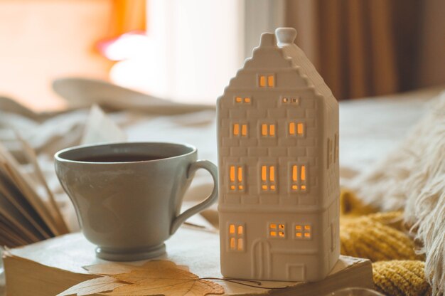 Détails de la vie encore à l'intérieur de la maison du salon. Chandails et tasse de thé avec une bougie et un décor d'automne sur les livres. Lisez, reposez-vous. Concept d'automne ou d'hiver confortable.