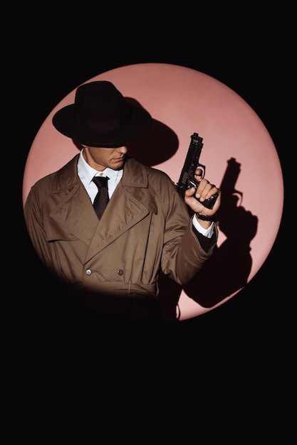 Photo détective masculin en manteau et chapeau avec silhouette de pistolet dans le style des livres d'espionnage de films de détective des années 1950