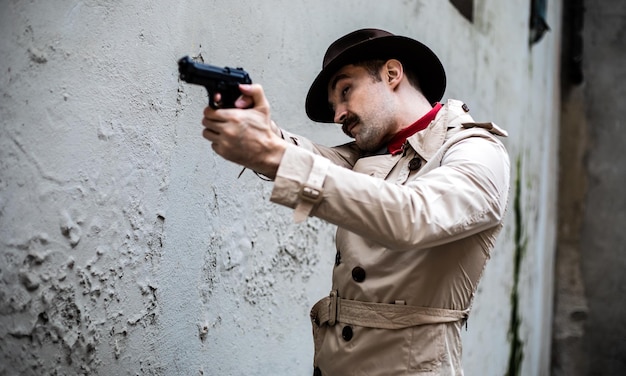 Un détective en trench-coat qui vise avec un pistolet.