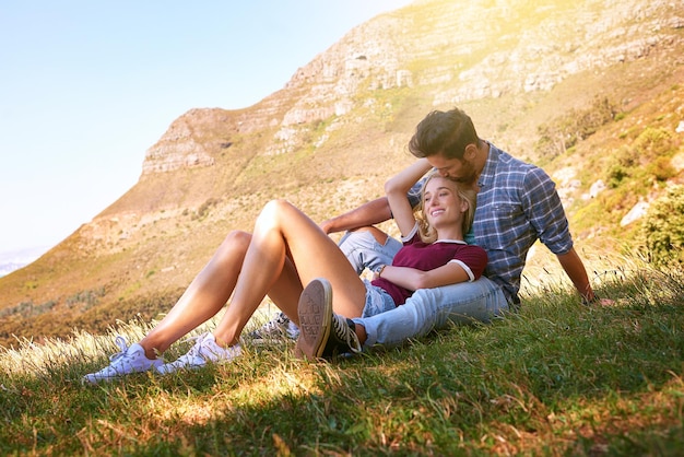 Détendez-vous baiser et heureux avec un couple dans la nature pour des liens insouciants et affectueux Bonheur rendez-vous et romance avec un homme et une femme câlins dans un champ d'herbe pour les vacances d'été amour et montagnes