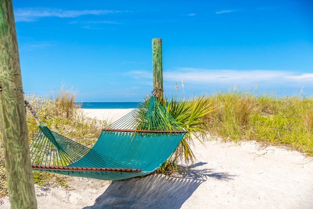 Photo détendez-vous avec un hamac vide et fond de l'océan sur une plage tropicale.