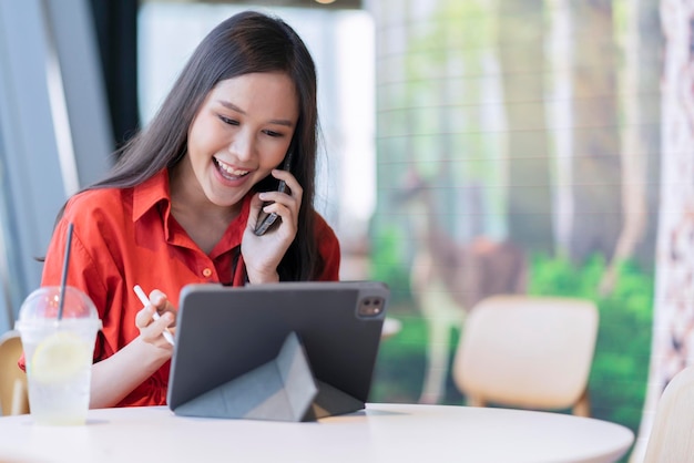 Détendez-vous loisirs séduisante femme entrepreneure indépendante asiatique intelligente sourire et profiter de travailler avec un smartphone et un ordinateur portable au café avec le concept d'idées décontractées nomade numérique d'affaires de la ville floue