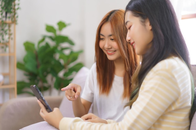 Détendez-vous à la maison concept couple lesbien LGBT point et regarde sur smartphone tout en travaillant ensemble