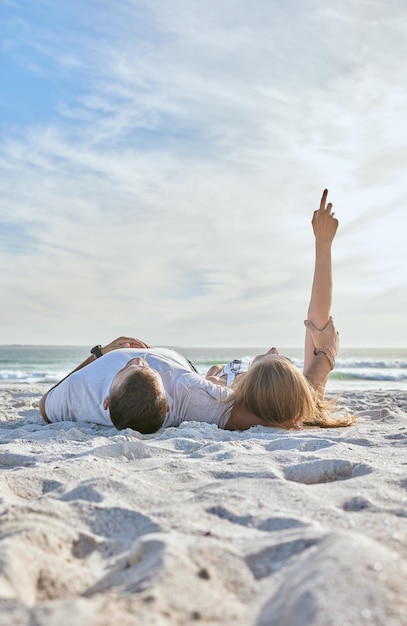 Détendez-vous sur la plage et couple regardant le ciel lors d'une aventure ou d'un voyage en bord de mer Voyagez calmement et homme et femme se reposant ensemble dans la nature au bord de l'océan pendant des vacances en Australie