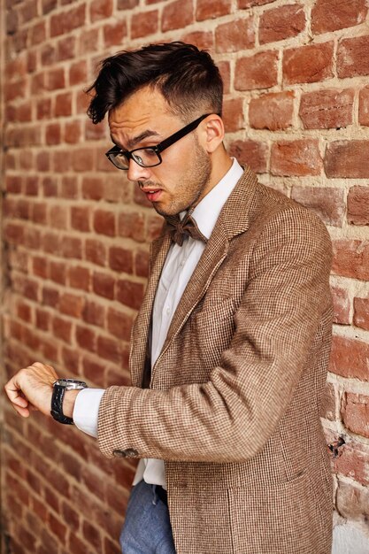 Détendu confiant beau jeune homme debout il regarde sur une horloge