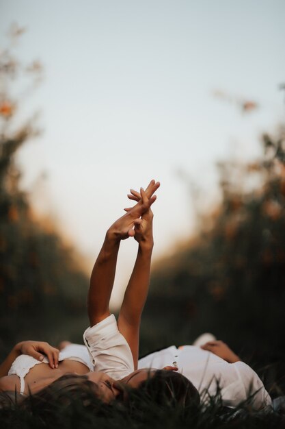 Détendu jeune couple allongé sur la pelouse verte, s'embrassent les yeux fermés et se tenant la main.