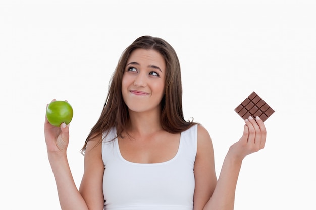 Détendu jeune femme tenant une pomme et du chocolat