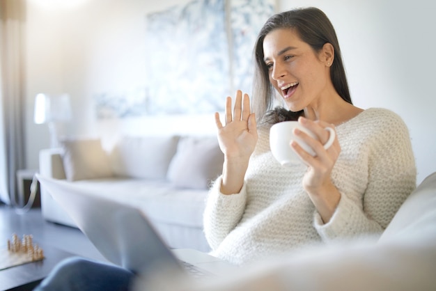 Détendue belle brune avec un ordinateur portable à la maison