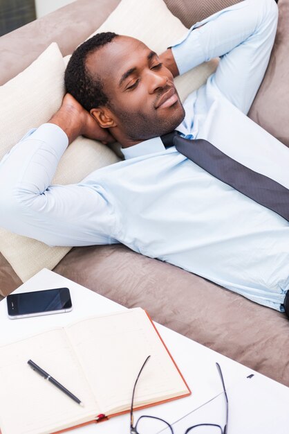 Détente après le travail. Vue de dessus du beau jeune homme africain en chemise et cravate