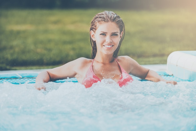 Détente dans le bain à remous. Jolie jeune femme en bikini se détendre dans un bain à remous et souriant