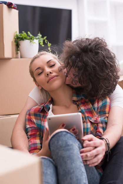 Détente dans une nouvelle maison. Enthousiaste jeune couple assis sur le sol tandis que des boîtes en carton s'étendent tout autour d'eux