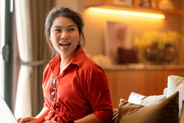 Détente décontractée portrait souriant femme asiatique propriétaire d'une maison tissu décontracté assis sur un canapé à la maison avec une expression positive souriante paisible sentiment facialrester à la maison avec bonheur sourire paisible