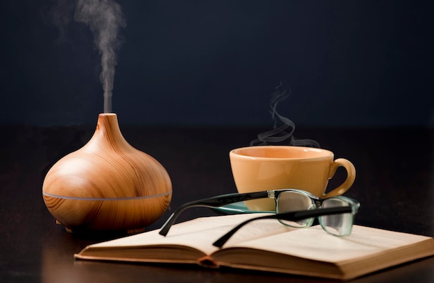 Détente à la maison avec diffuseur d'huile d'aromathérapie tasse de thé jaune lunettes de lecture Aroma esse