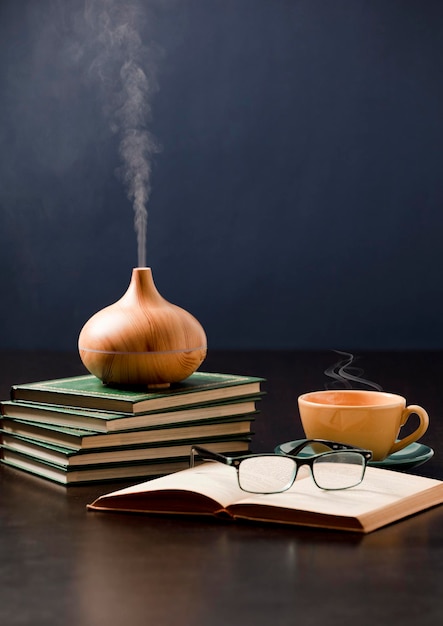 Détente à la maison avec diffuseur d'huile d'aromathérapie tasse de thé jaune lunettes de lecture Aroma esse