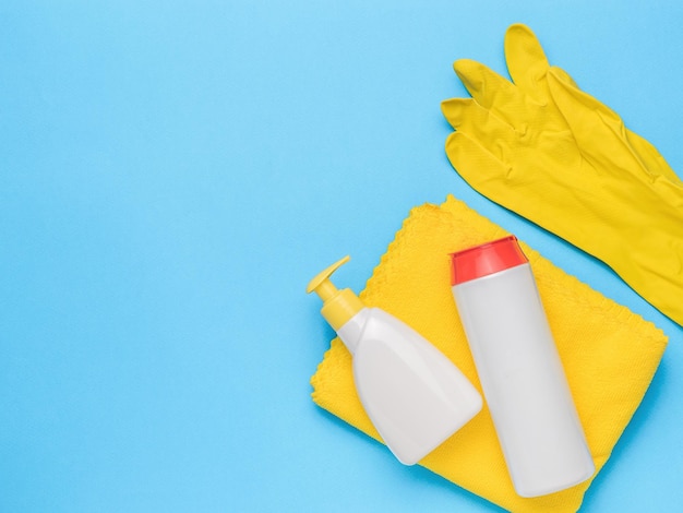 Détergents un chiffon jaune et des gants jaunes sur fond bleu Kit de nettoyage