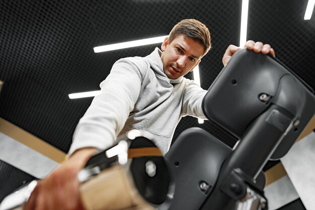 Déterminé beau jeune homme travaillant dans une salle de sport avec des haltères