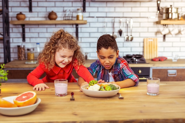 Le detesté. Fille émotive poussant le bol tout en refusant de manger du brocoli