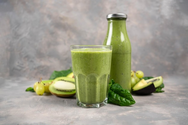 Detox Cleanse Drink Concept Ingrédients de smoothie aux légumes verts Jus sain biologique naturel en bouteille pour un régime de perte de poids ou un jour de jeûne Concombre, pomme, citron vert et mélange d'épinards isolé sur blanc