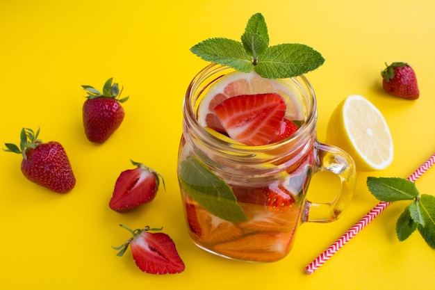 Détox ou eau infusée à la fraise et au citron dans le verre sur le jaune