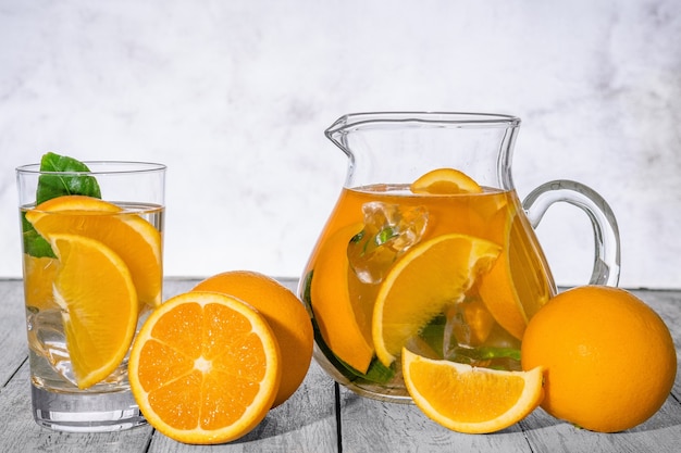 Detox orange saine avec orange fraîche et citron vert, en verre sur un mur en bois.