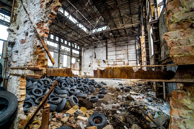 Détruit l'ancienne usine avec des ordures et une pile de pneus en caoutchouc usés à l'intérieur.