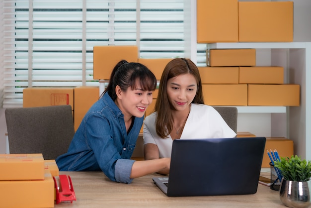 Deux adolescentes asiatiques propriétaire femme d'affaires travaillent assis sur la table pour les achats en ligne, vérifier l'ordre de livraison du courrier avec du matériel de bureau, concept de style de vie d'entrepreneur