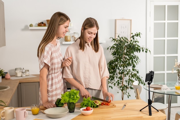 Deux adolescentes cuisinant une salade de légumes pendant le livestream