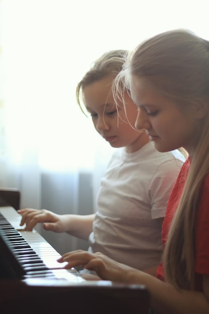 Deux adolescentes sœurs de 14 ans jouent du piano à la maison, plan vertical, gros plan