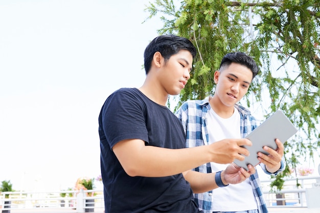 Deux adolescents asiatiques utilisant une tablette numérique ensemble dans la ville