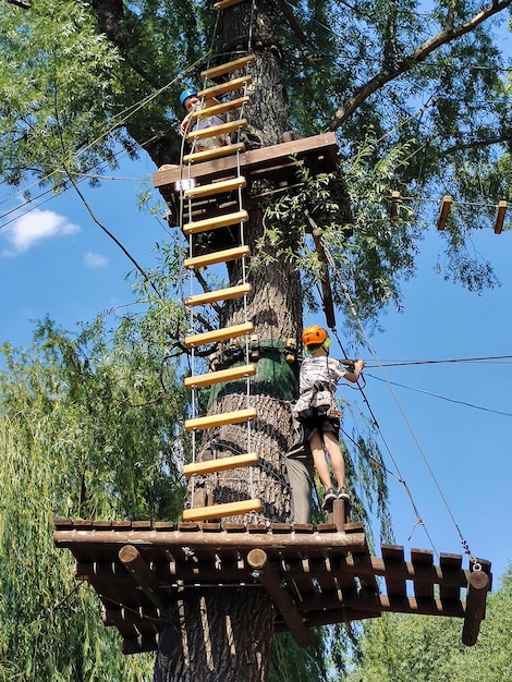 Deux adolescents sur une échelle de corde jusqu'au sommet d'un arbre dans un parc à cordes en munitions de sécurité