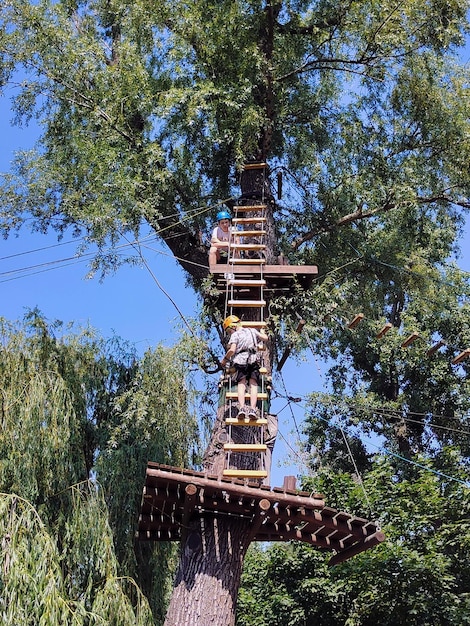 Deux adolescents grimpent sur une échelle de corde dans un parc d'attractions de corde d'été Vue de dessous