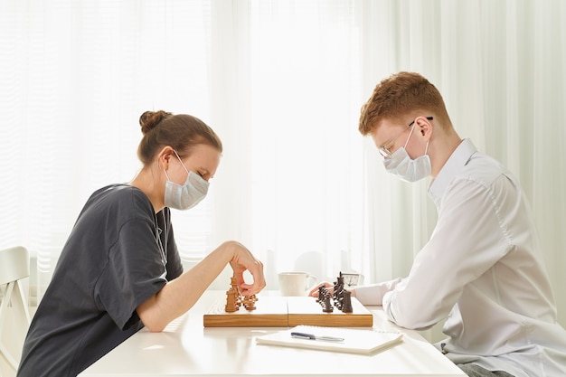 Photo deux adolescents jouent aux échecs pendant la quarantaine en raison de la pandémie de coronavirus