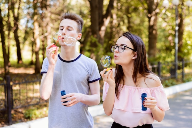 Deux adolescents s'amusant dans le parc par une belle journée d'été ensoleillée, faisant des bulles