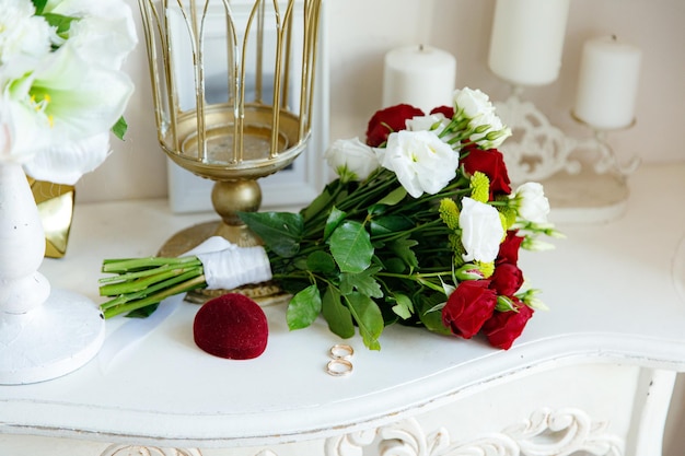 Deux alliances en or blanc et rouge avec un bouquet de mariée avec des roses rouges