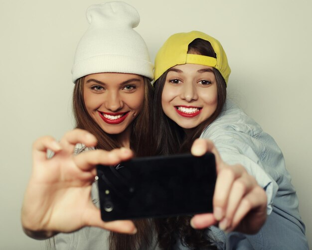 Deux amies adolescentes en tenue hipster se font selfie