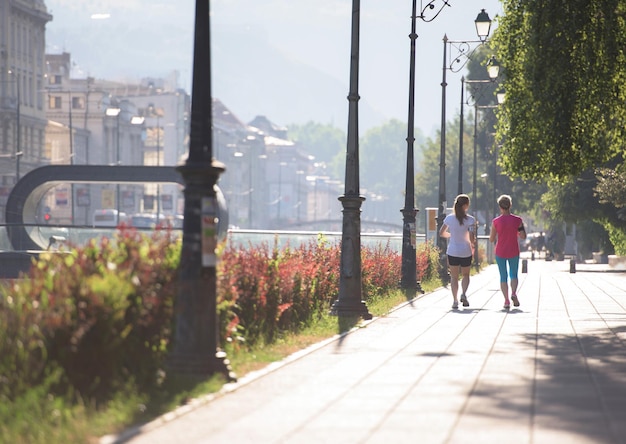 deux amies d'âge moyen font du jogging le matin avec le lever du soleil en arrière-plan