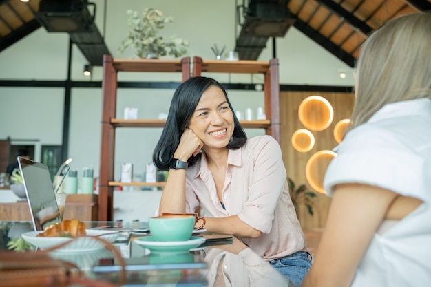 Deux amies buvant du café dans le café. Deux femmes au café, parlant, riant et profitant de leur temps. Concepts de mode de vie et d'amitié avec de vrais modèles de personnes.