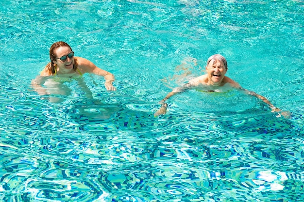 Deux amies caucasiennes matures s'amusent dans une piscine en plein air sous la lumière du soleil.