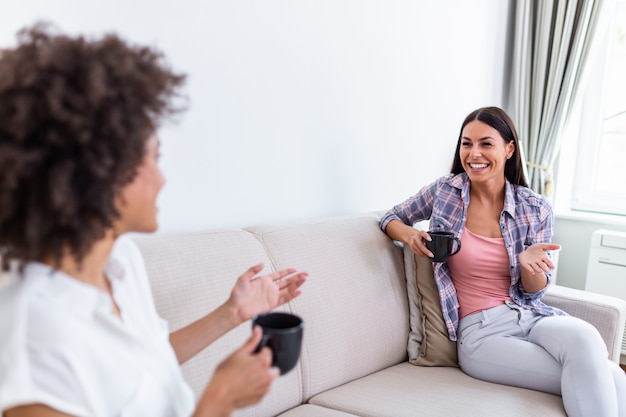 Deux amies en distanciation sociale assis sur un canapé.